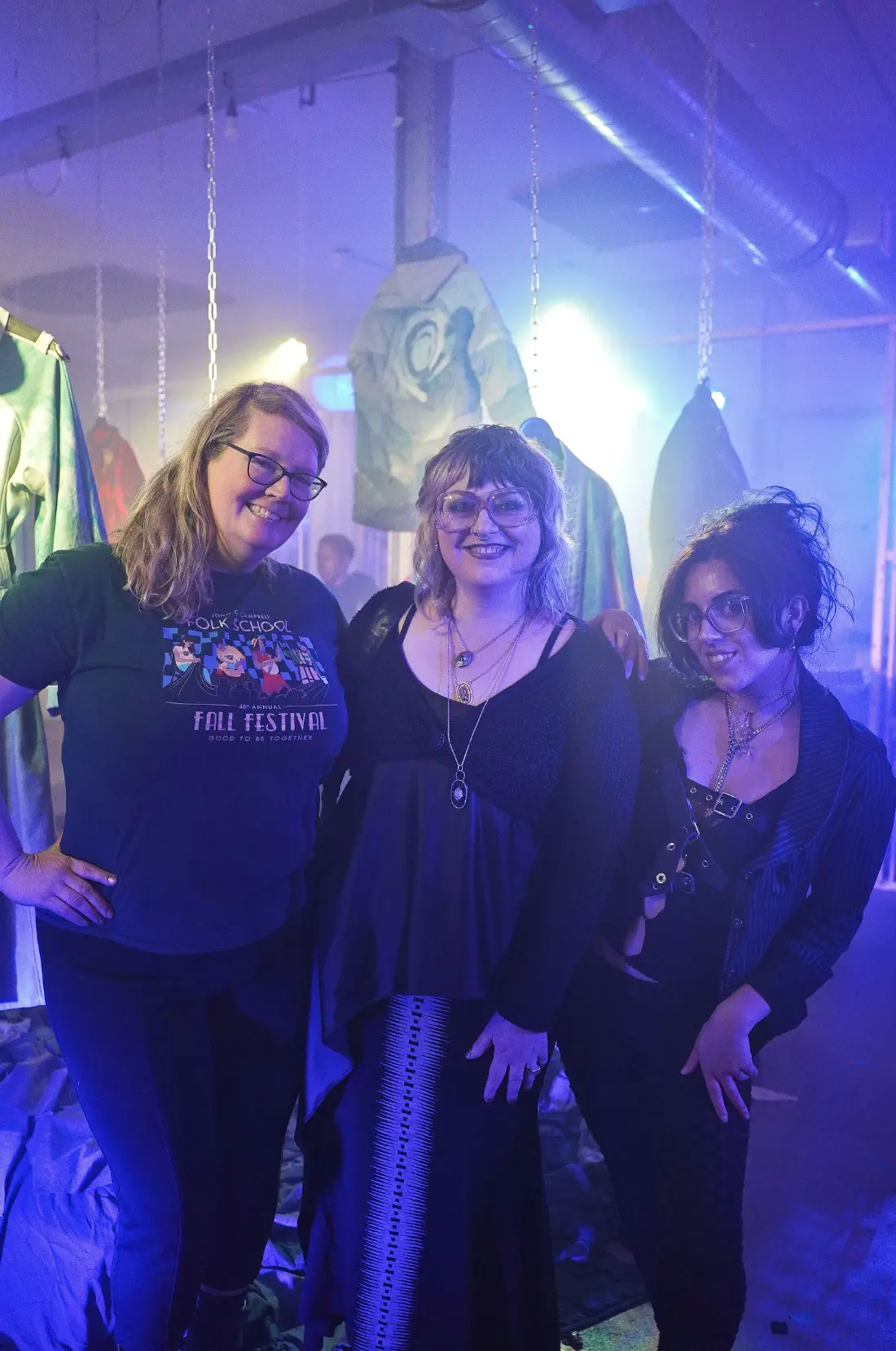 Three visitors posing among the suspended jackets at Collective Power