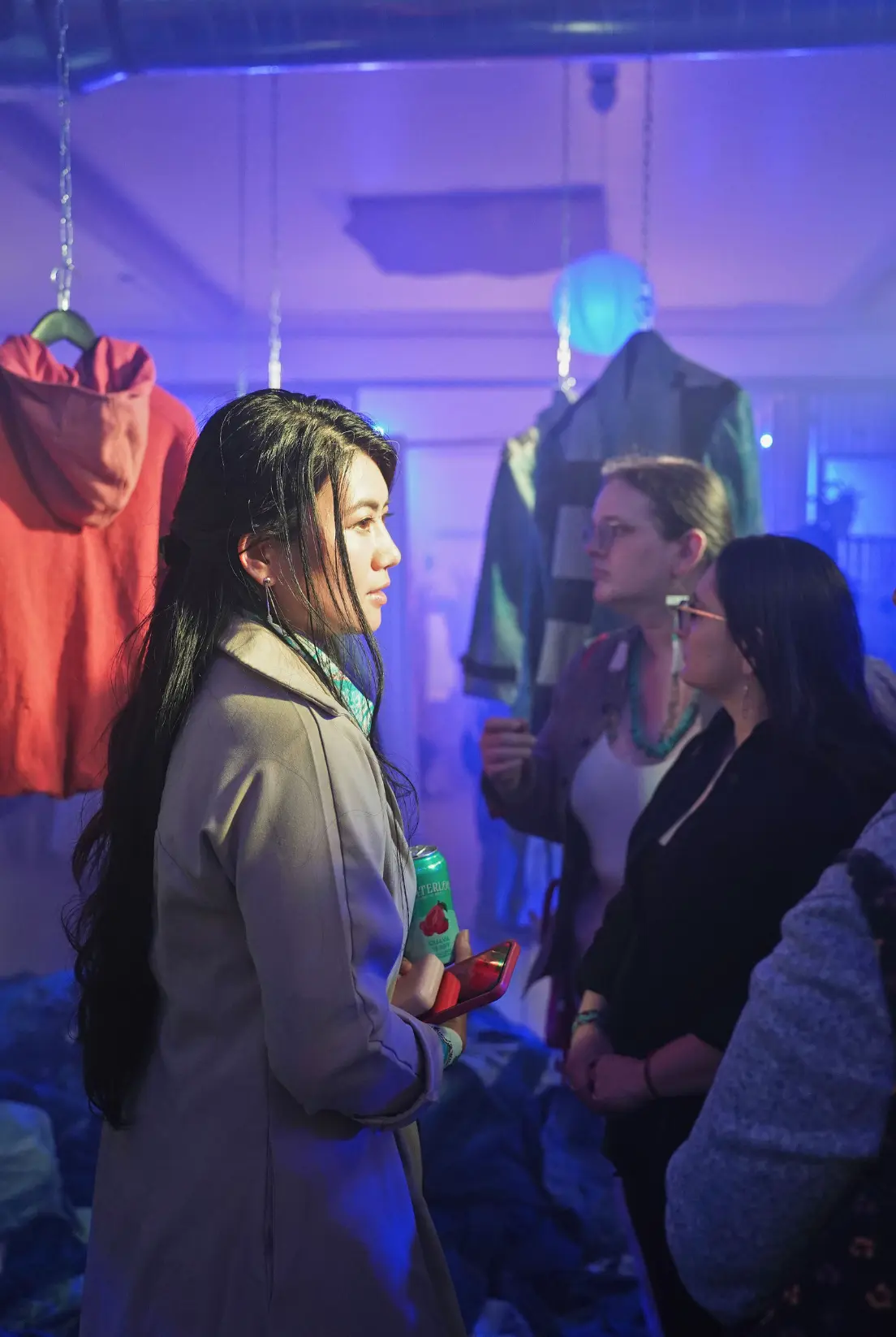 Visitors in conversation among the suspended garments at Collective Power